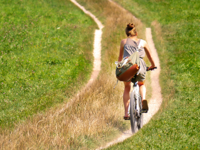 A woman on a bike cycling on a hilly path