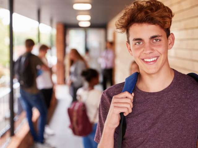Teenage boy at college smiling.