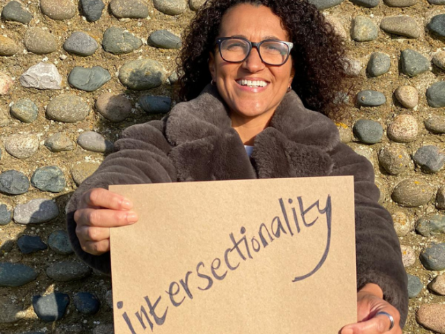 Photo of local life coach Sam Adams holding a notice reading 'Intersectionality'.