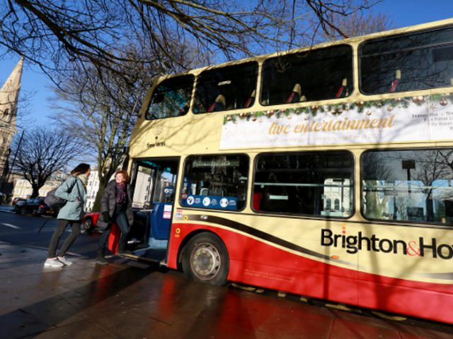 A bus parked on the side of the road with two passengers getting on