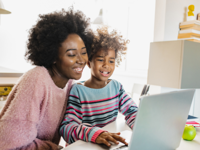 Mother and daughter doing online learning together working on a laptop