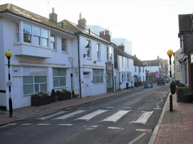 A picture of a road with a zebra crossing and buildings on either side