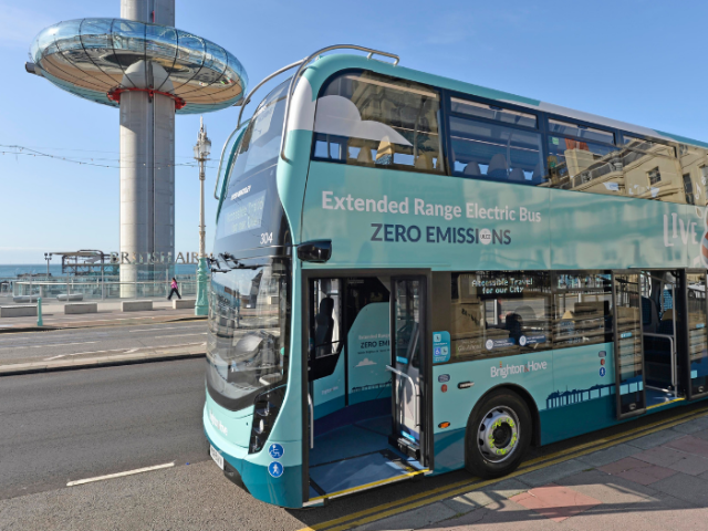 Green and blue bus on a road with the i360 in the background