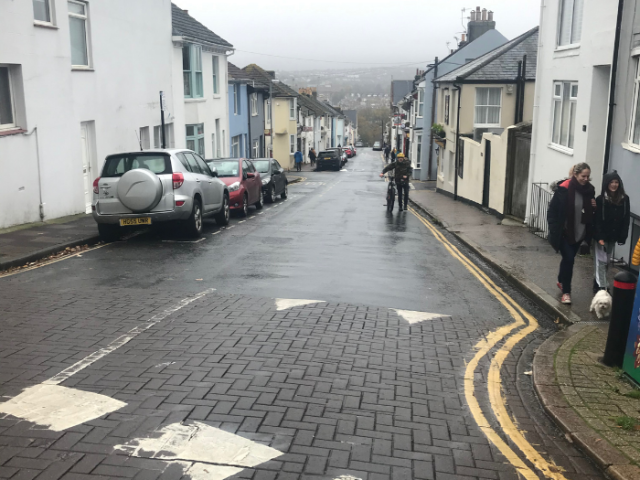 Street in Hanover area of Brighton, showing traffic calming hump, people in street and cyclist