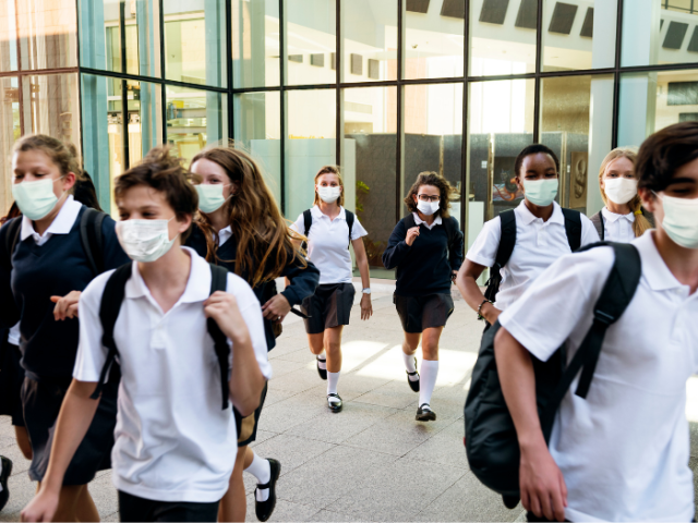 Group of school children walking in school uniform and masks