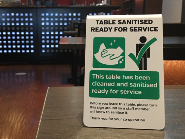 Photo with a Covid safety sign in a bar saying that the table has been cleaned and is ready to use