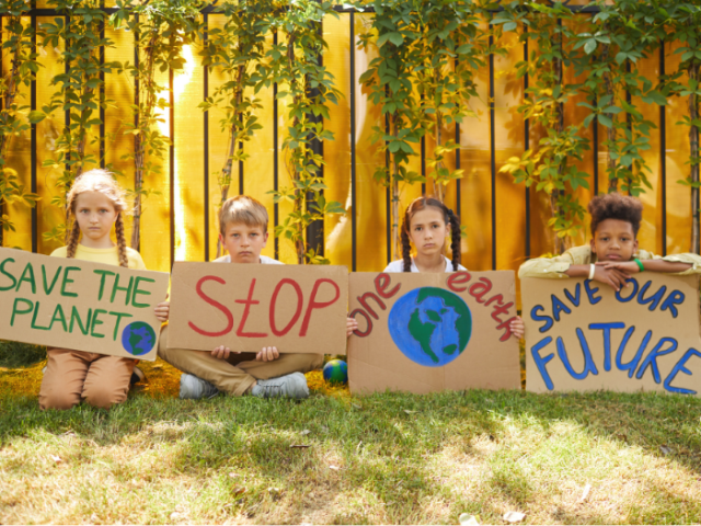 Four children holding up a banner each which says Save the Planet, Stop, One Earth, Save our Future