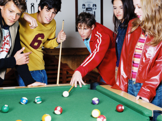 Group of 5 young people playing a game of billards 