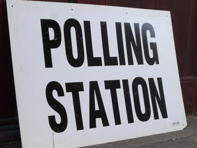Photo of a white sign with the words 'polling station' written in black writing