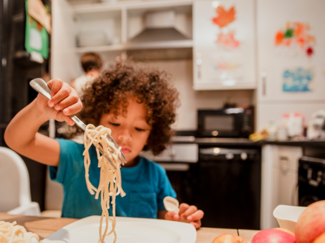 Young boy eating a bowl of spaghetti 