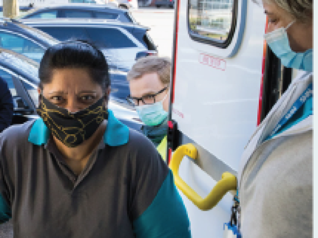 Woman entering mobile vaccination ambulance greeted by healthcare professional