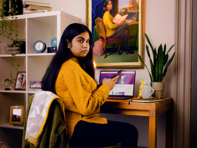 Young woman sitting at a desk with the census website open on her laptop and mobile phone