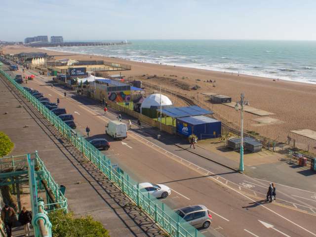 Long view of Madeira Drive on Brighton seafront with cars and temporary events buildings