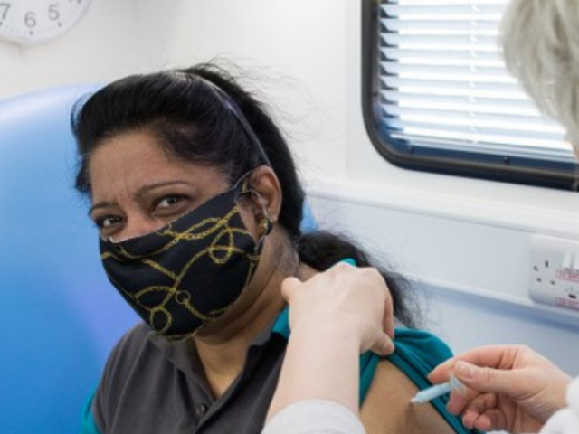 Woman wearing a face covering and getting a Covid vaccination