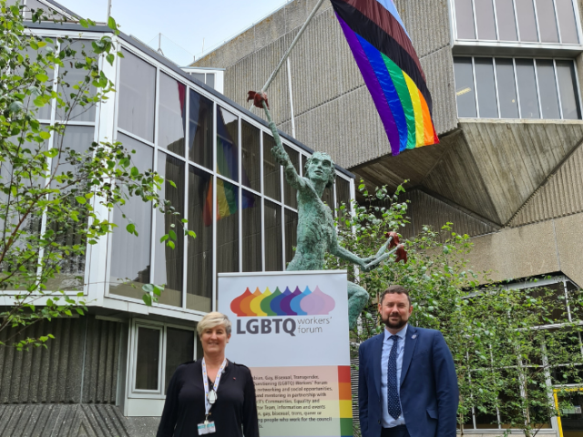 LGBTQ Workers&rsquo; Forum member Sahnni Collins and council leader Ph&eacute;lim Mac Cafferty beneath the inclusive Pride flag flying at Hove Town Hall 