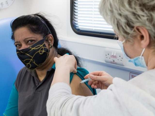 woman being vaccinated in mobile vaccination amulence, smiling at camera