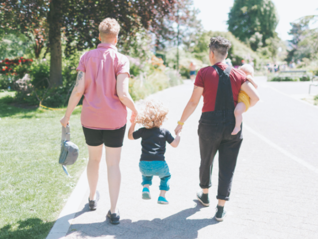 Two women walking with a child, one of the women is holding a baby