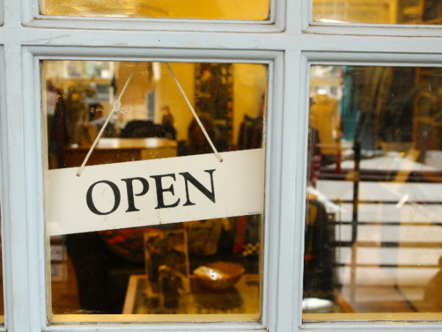 Shop window with an 'open' sign hanging in it, with gift shop interior.