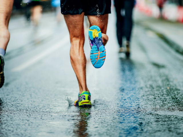 a person wearing shorts and trainers running along a wet road