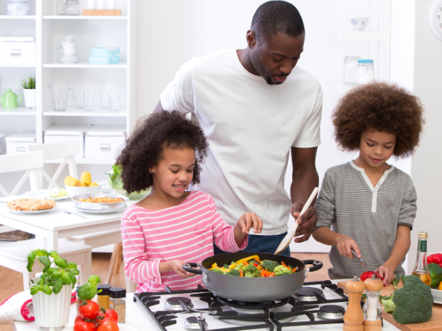 Two children and a man making a vegetable stir-fry