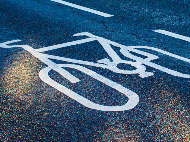 A picture of a road with a white cycle sign painted on it