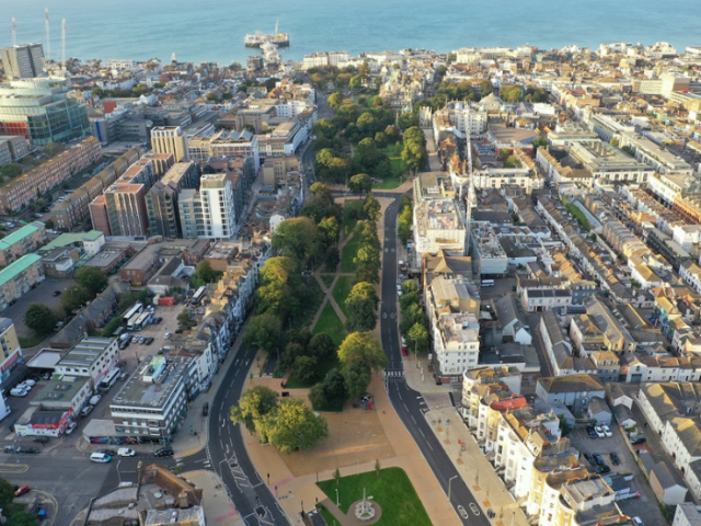 An picture from above showing trees, green spaces, houses and the sea