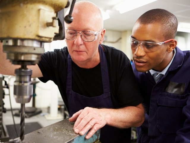 man showing young adult an engineering drill