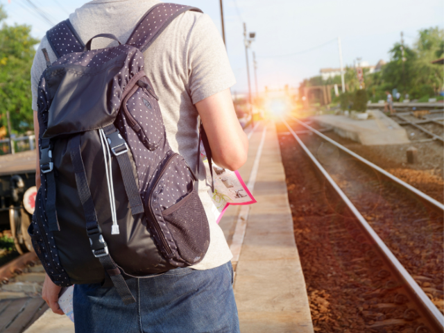 A picture of a man wearing a rucksack next to a railway line