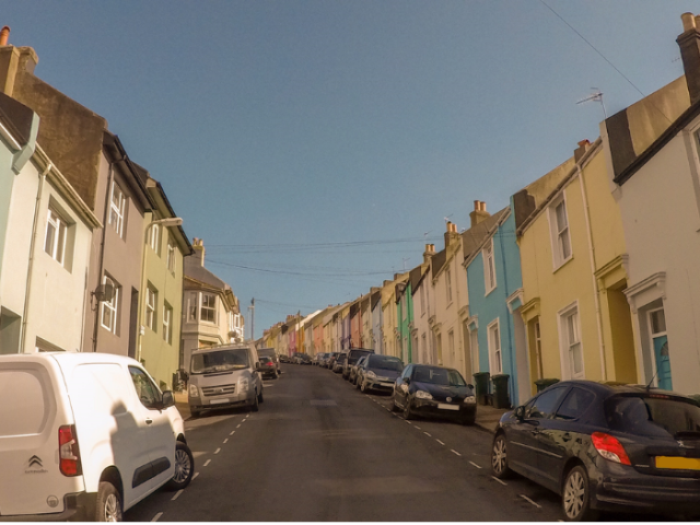 A road with terraced houses and cars on either side