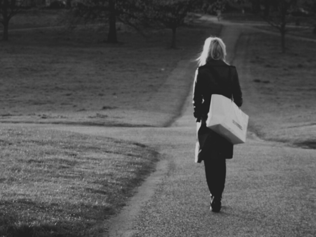 A woman walking alone on a path in the middle of a park