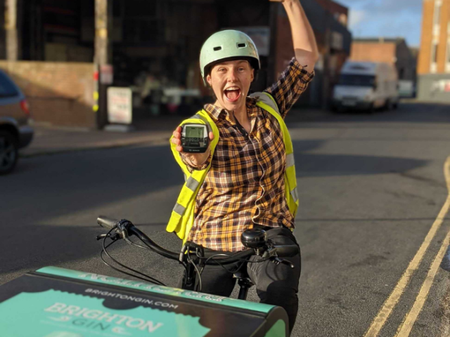 A woman sitting on a bike holding up a small black box