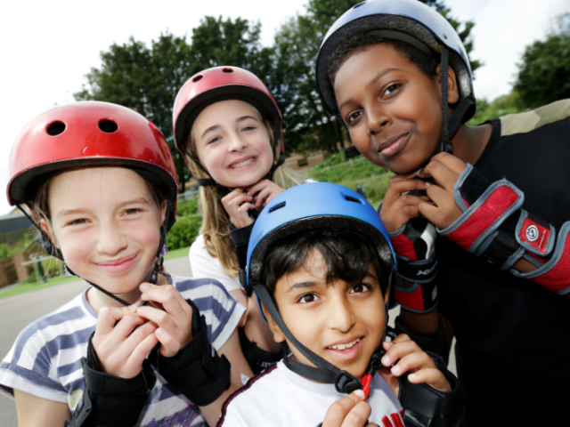 Children of different ages wearing skateboarding helmets