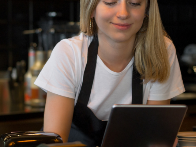 young girl wearing an apron, looking at an ipad