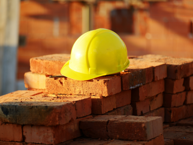 Construction worker's yellow safety hat on a pile of brown bricks