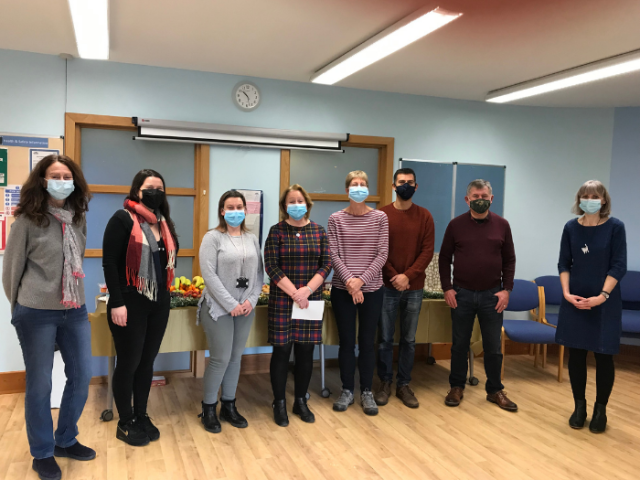 Five volunteers posing with Childrens' Centre staff in a room 