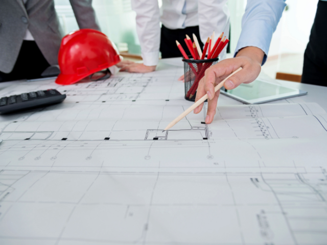 a hand pointing with a pencil on an architect's drawing