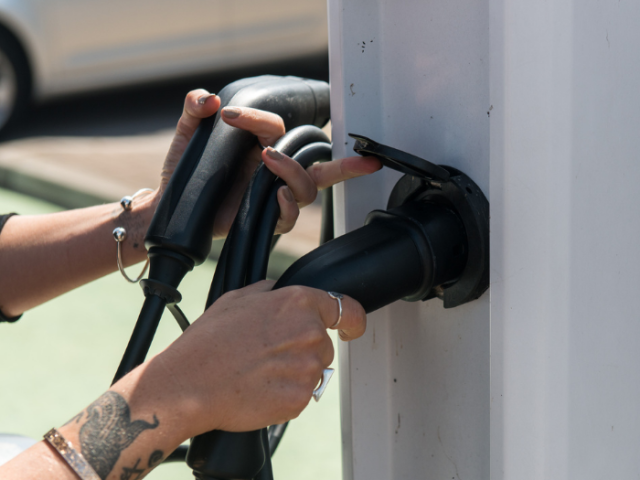 A picture of a person using an electric vehicle charger