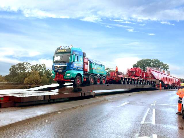 A picture of a large lorry being moved across a temporary bridge