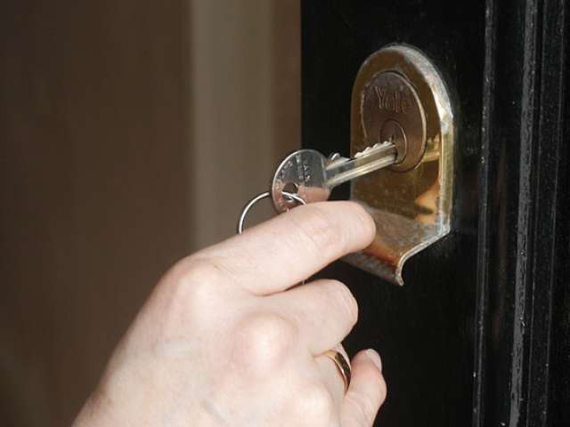 Hand putting key in door lock