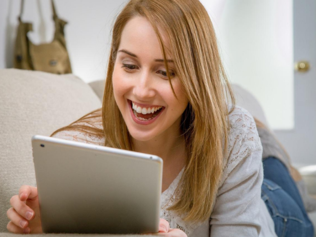 Lady looking at ipad and smiling, enjoying conversation 