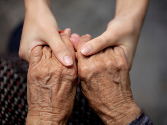 Picture of a younger person holding the hands of an older person