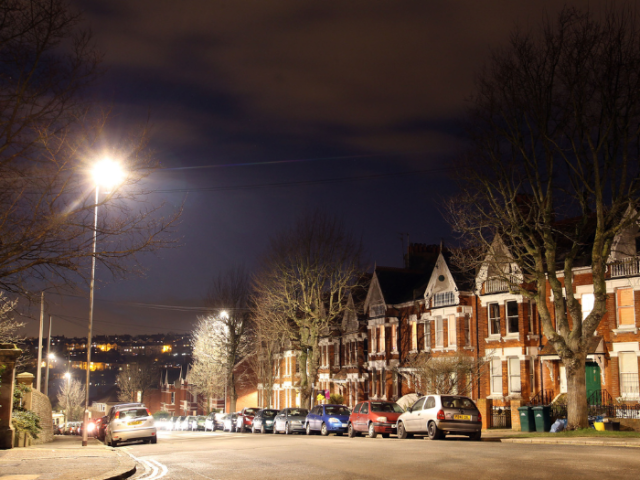 A picture of a street a night with houses and a streetlight