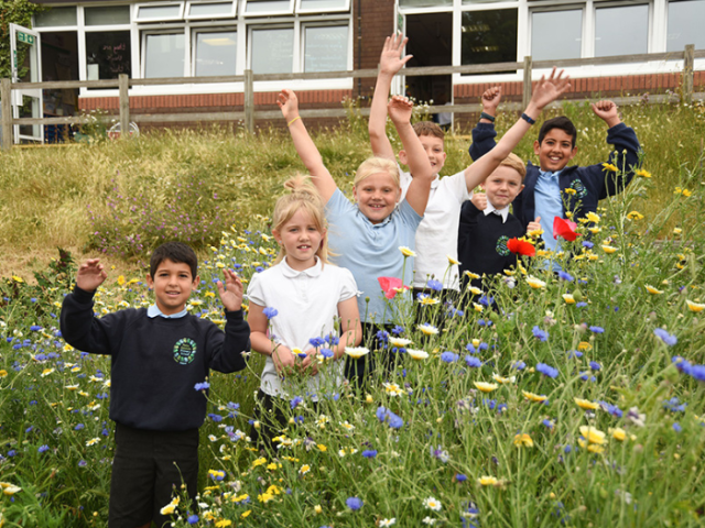Students from Peter Gladwin Primary School standing in a field of wildflowers.