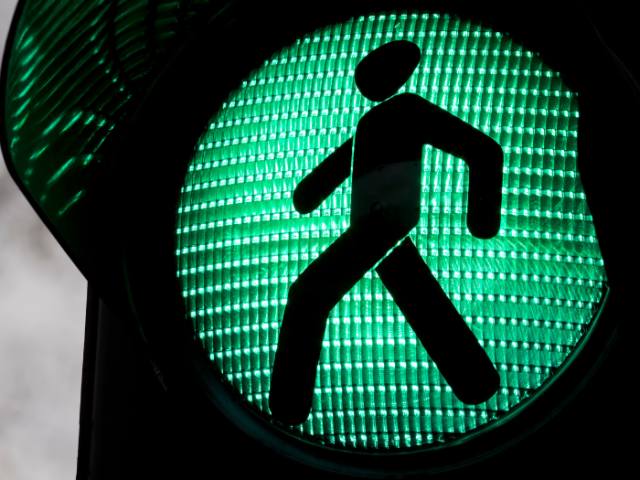 Close-up silhouette graphic of a person walking inside a green traffic light