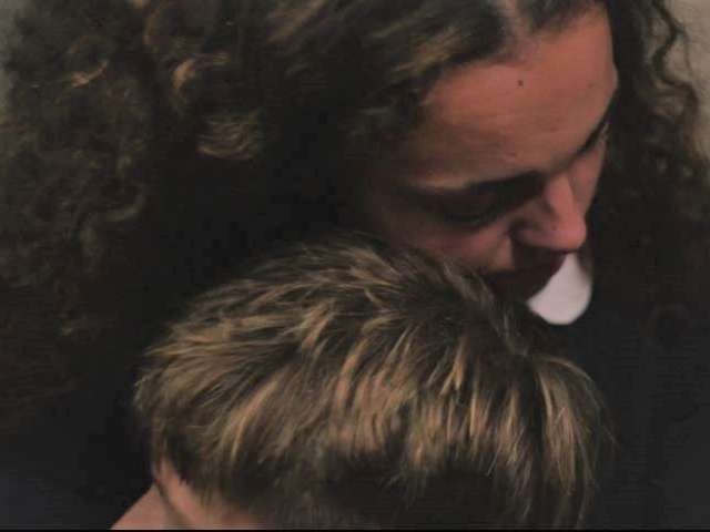 Image of an older sister hugging her younger brother