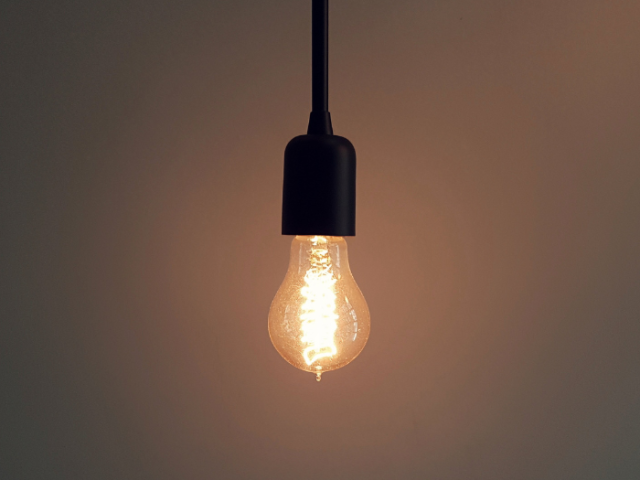 Photo of a switched-on light bulb hanging down from a cable