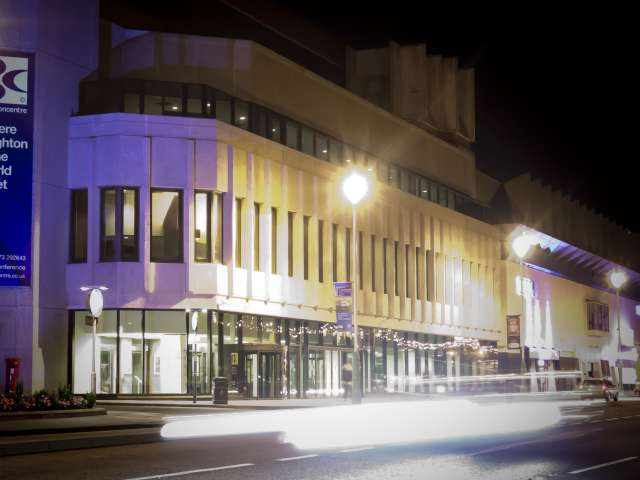 The Brighton Centre exterior taken at night, lit up purple and white