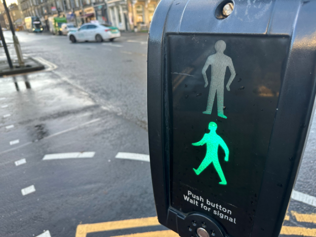 A green 'walk' signal on a pedestrian crossing