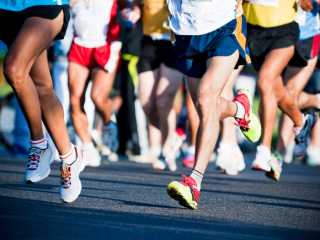 legs of runners wearing shorts taking part in a marathon 
