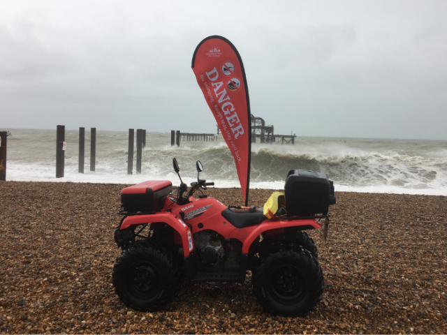 Picture of a quad bike on the beach with a Danger banner